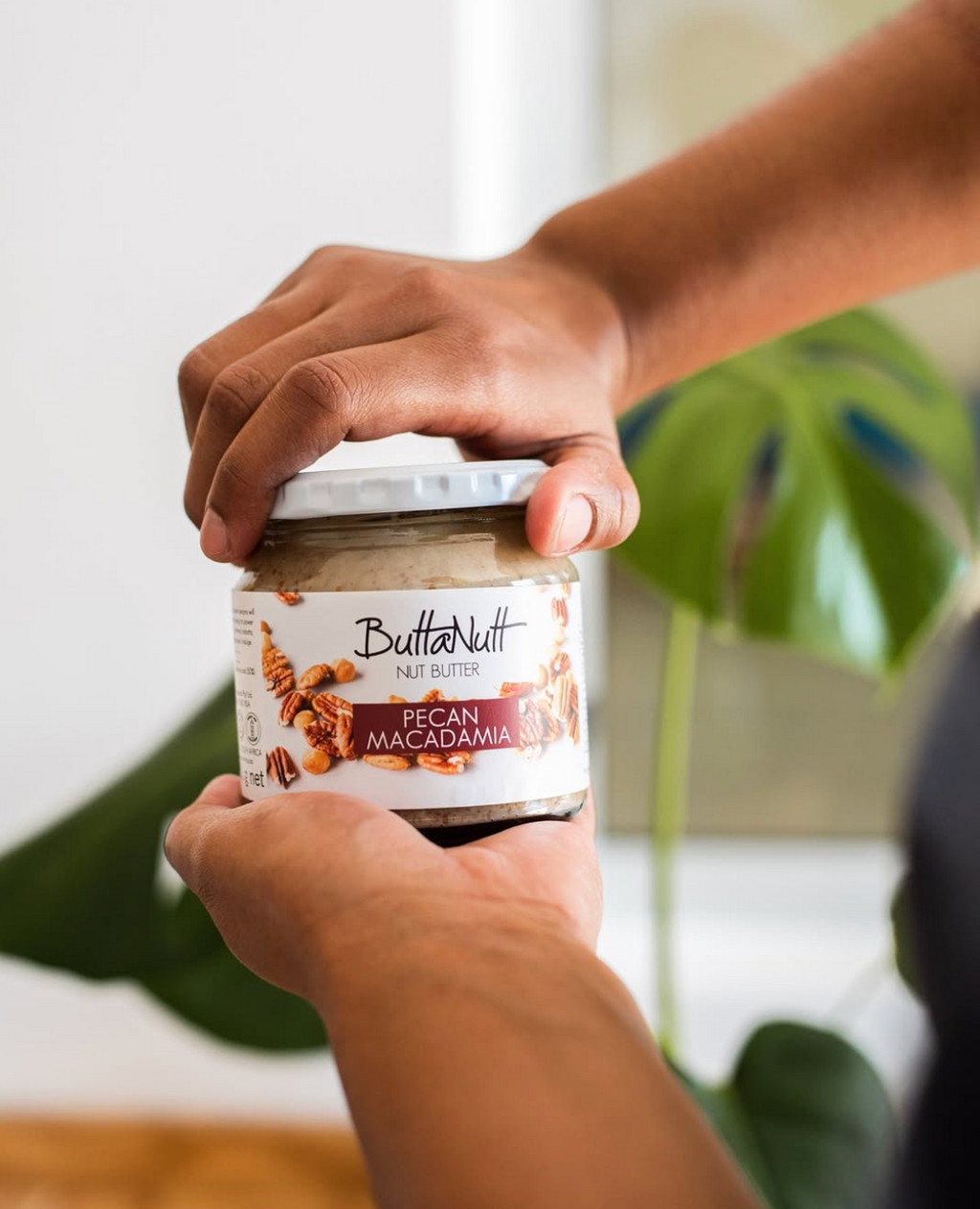 Hands holding a jar of pecan and macadamia nut butter — Food Trader